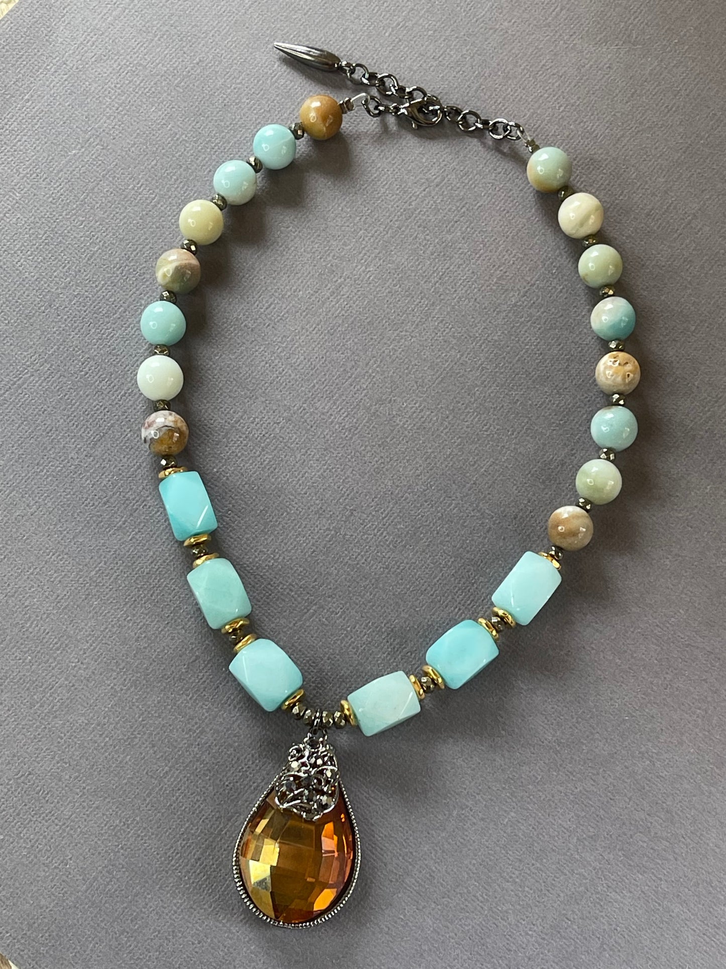 Handmade amazonite gemstone necklace with gold tone bead spacers and a sparkling faceted pendant in a gunmetal tone crown-style frame