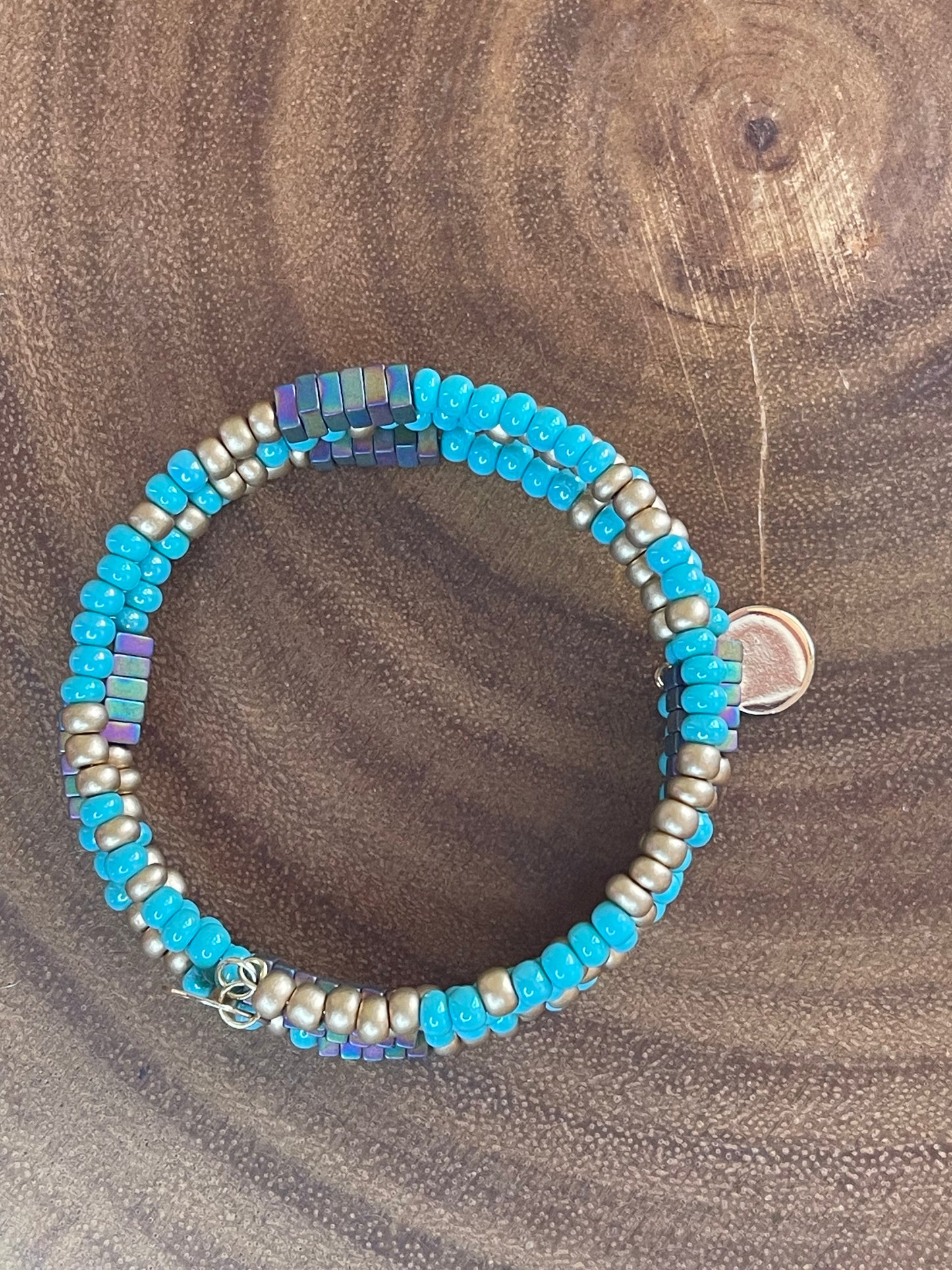 Turquoise and gold tone seed bead wrap bracelet with colorful hematite cube beads and a round charm.