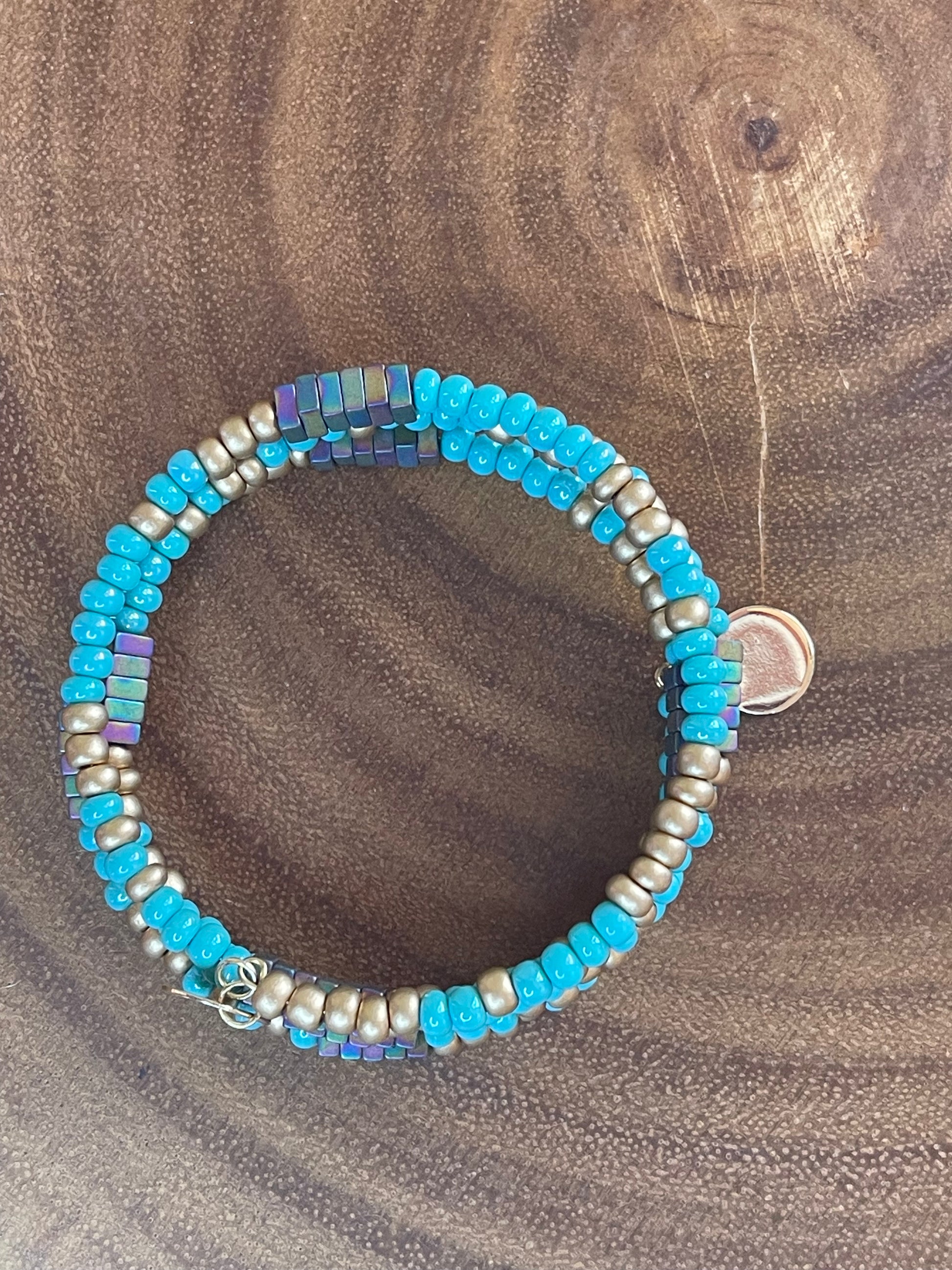 Turquoise and gold tone seed bead wrap bracelet with colorful hematite cube beads and a round charm.