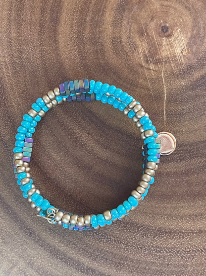 Turquoise and gold tone seed bead wrap bracelet with colorful hematite cube beads and a round charm.