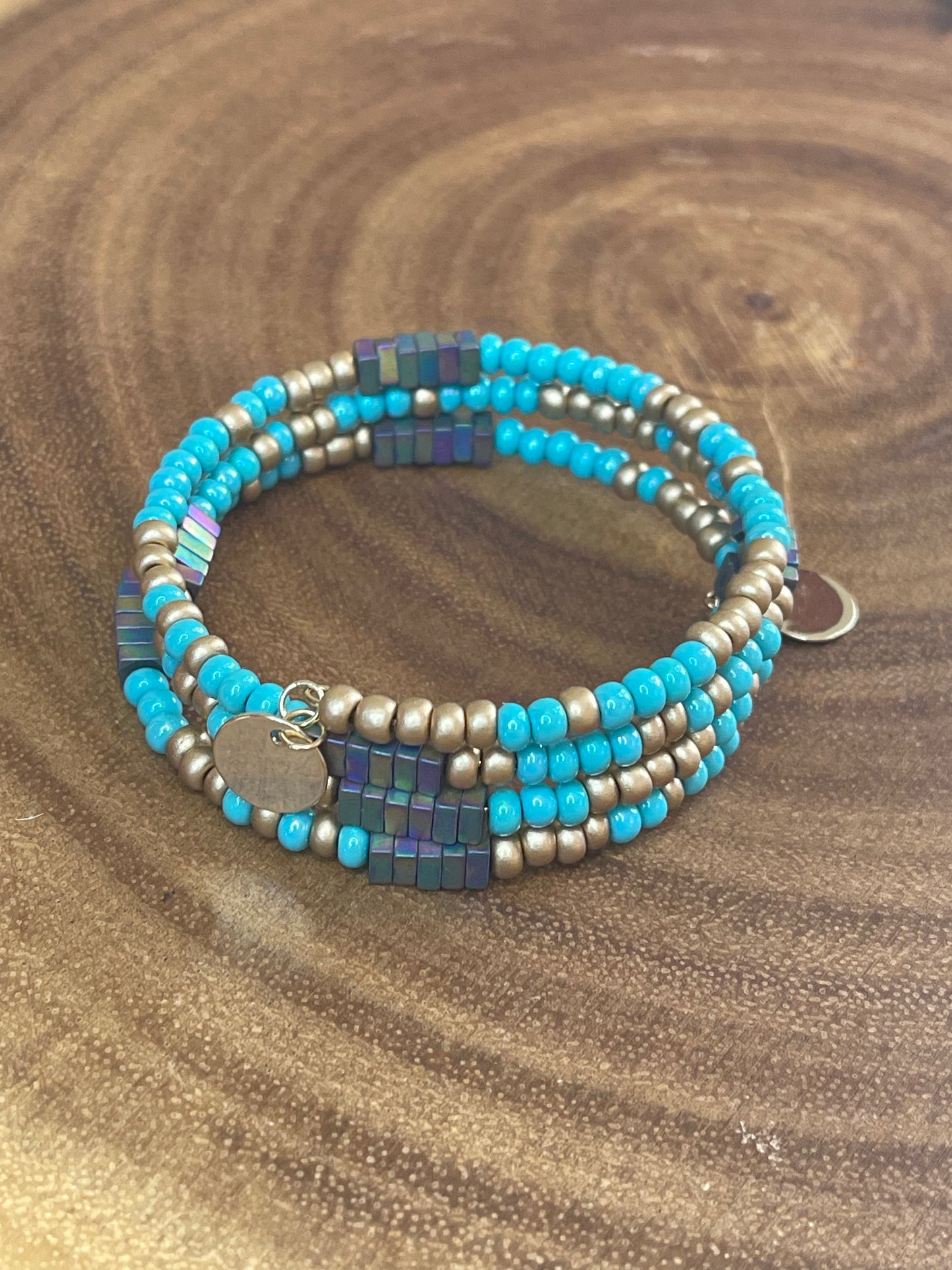 Turquoise and gold tone seed bead wrap bracelet with colorful hematite cube beads and a round charm.