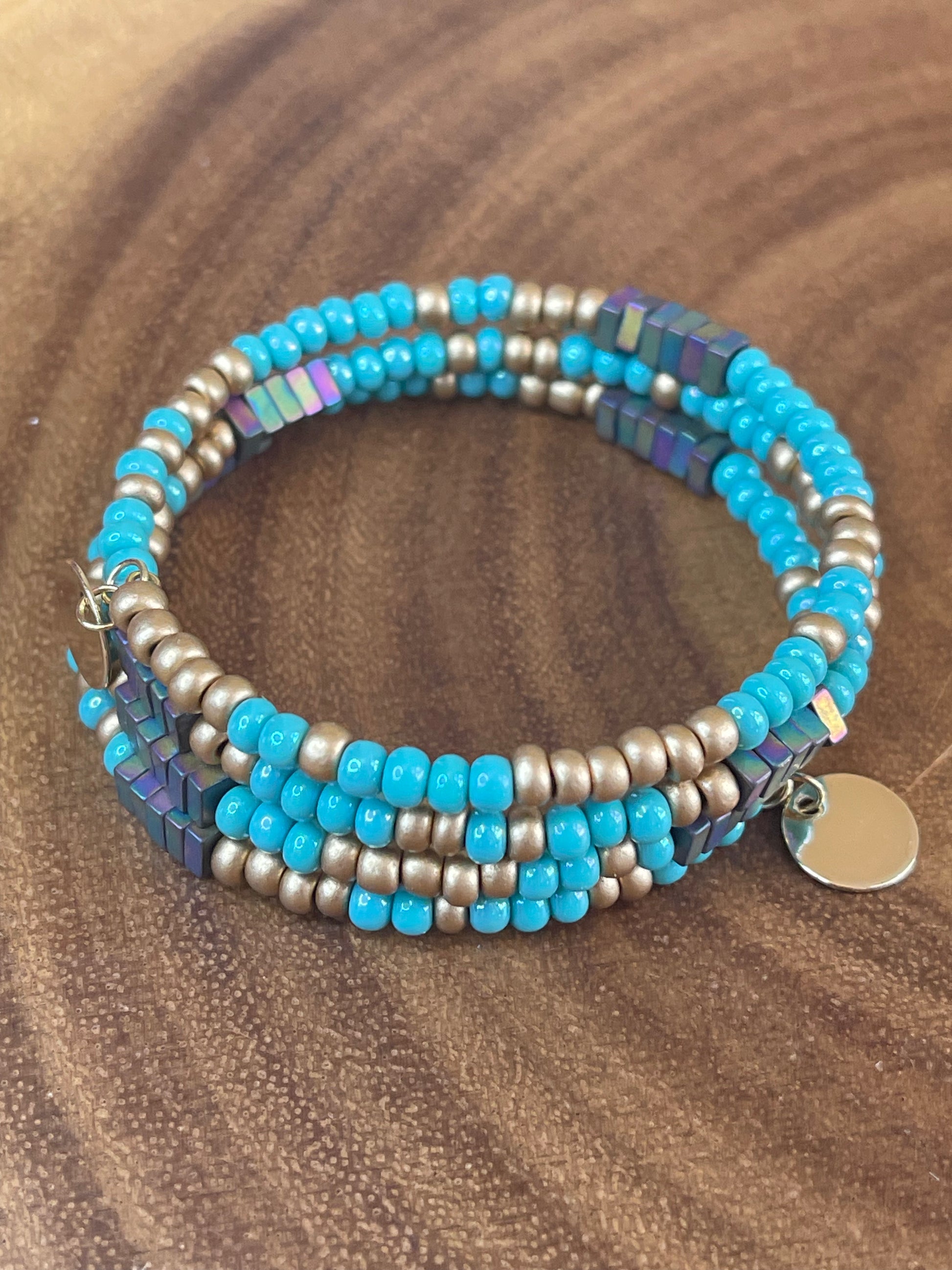 Turquoise and gold tone seed bead wrap bracelet with colorful hematite cube beads and a round charm.