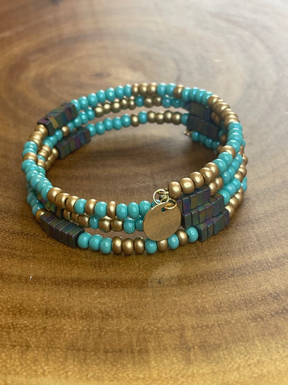 Turquoise and gold tone seed bead wrap bracelet with colorful hematite cube beads and a round charm.