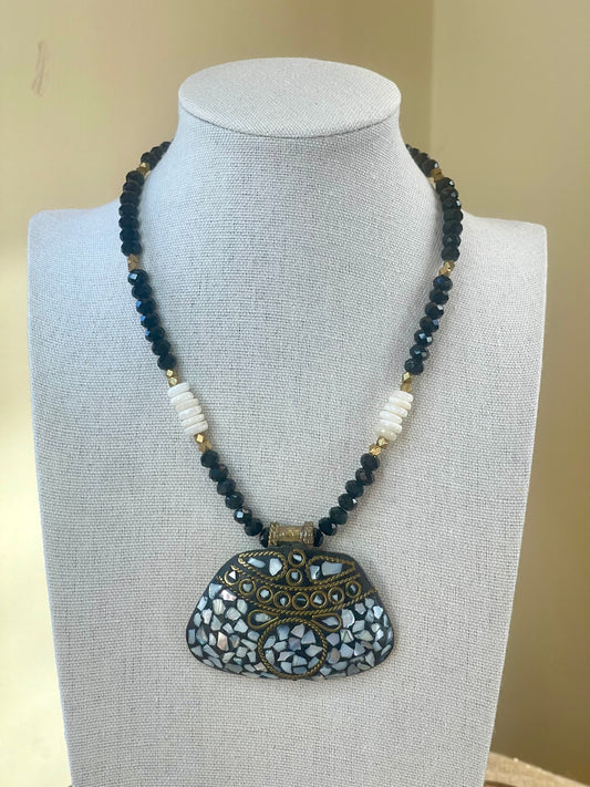 Black crystal and white shell pendant necklace displayed on jewelry bust.