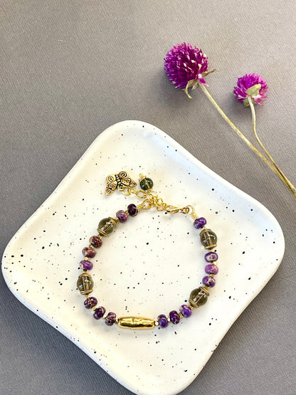 Purple imperial jasper and smoky quartz beaded bracelet with a textured gold tone bar and butterfly charm
