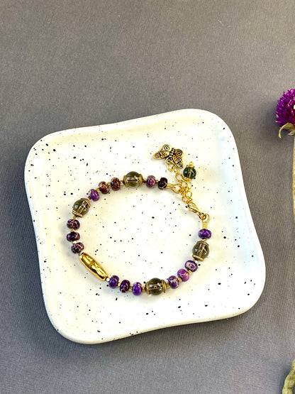 Purple imperial jasper and smoky quartz beaded bracelet with a textured gold tone bar and butterfly charm
