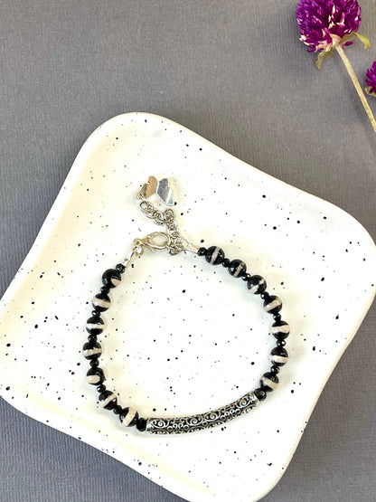  Black and white striped agate bead bracelet with an ornate silver plated bar and charm
