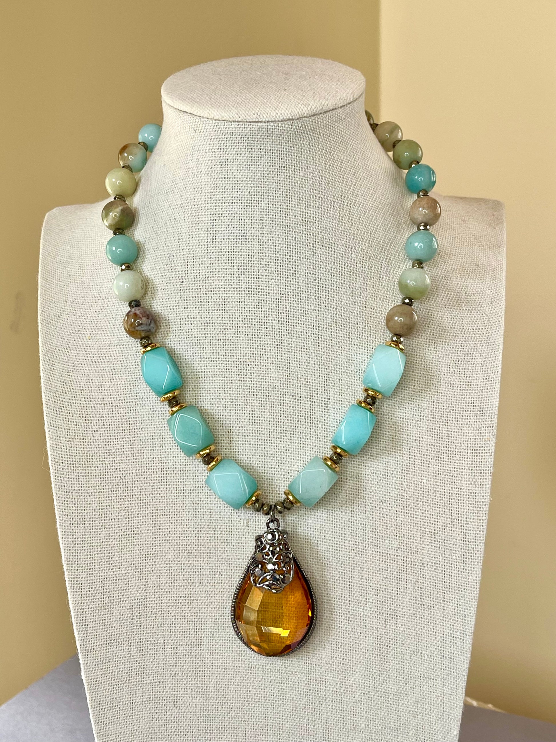 Handmade amazonite gemstone necklace with gold tone bead spacers and a sparkling faceted pendant in a gunmetal tone crown-style frame