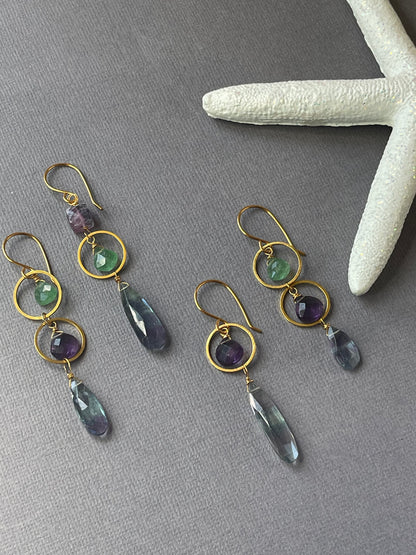 Closeup of dangle earrings featuring green strawberry quartz, amethyst and fluorite.