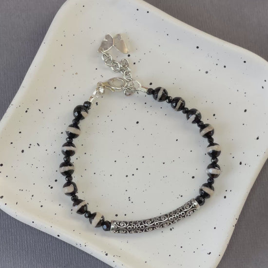 Black and white striped agate bead bracelet with an ornate silver plated bar and charm
