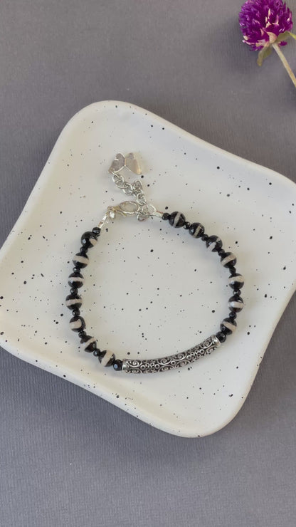 Black and white striped agate bead bracelet with an ornate silver plated bar and charm

