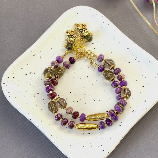 Purple imperial jasper and smoky quartz beaded bracelet with a textured gold tone bar and butterfly charm
