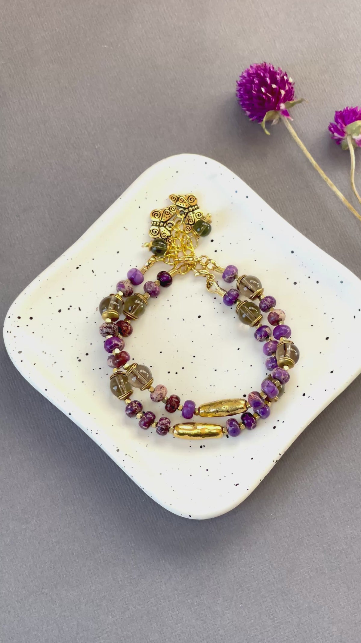 Purple imperial jasper and smoky quartz beaded bracelet with a textured gold tone bar and butterfly charm
