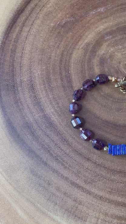 Close up of garnet gemstone beads and blue accents on bracelet