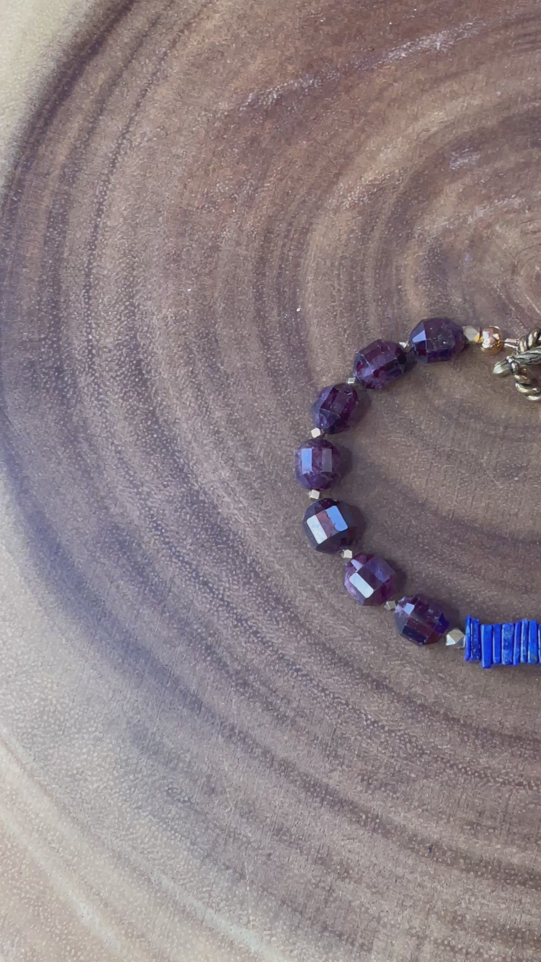 Close up of garnet gemstone beads and blue accents on bracelet